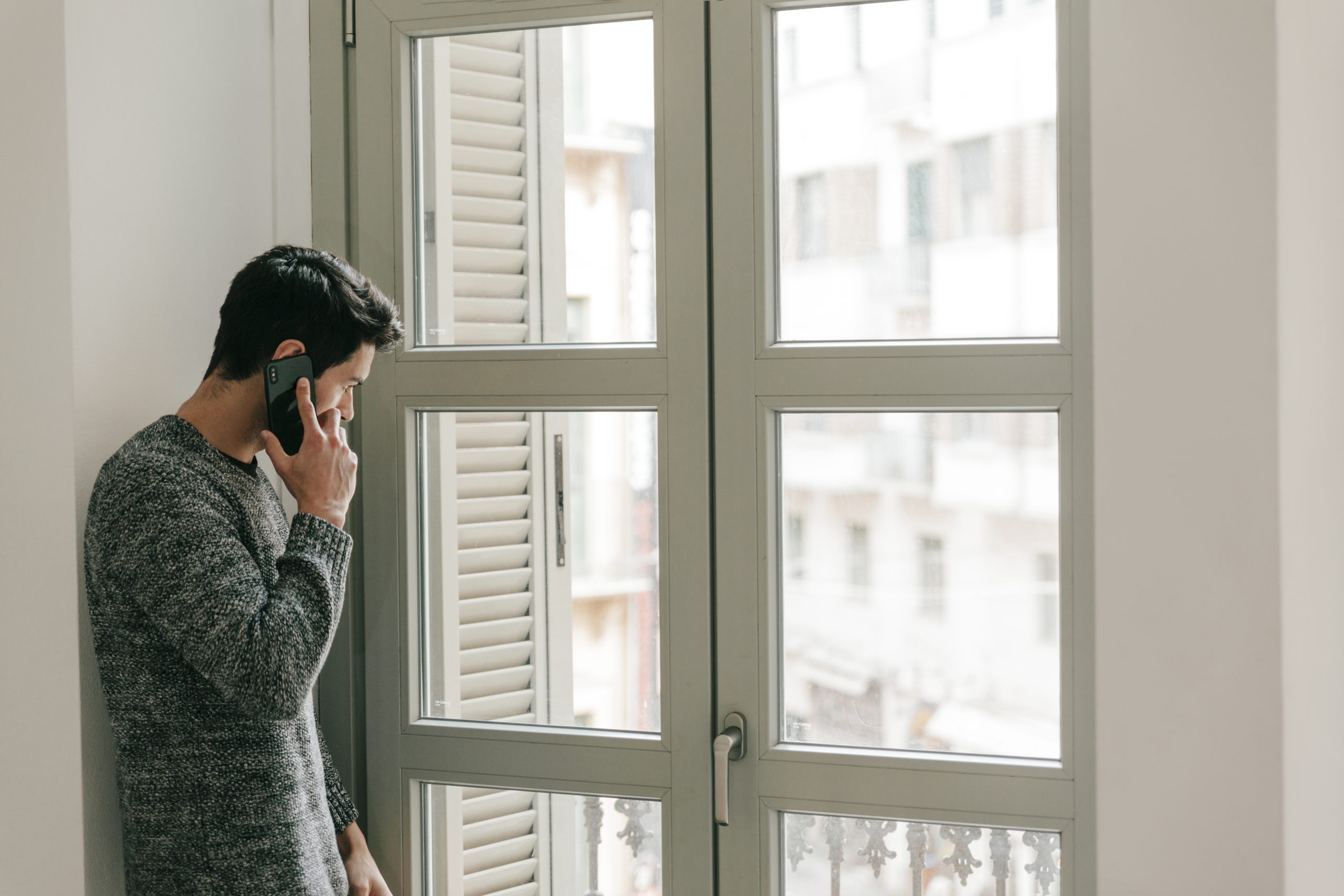 hombre-hablando-por-telefono-cerca-de-la-ventana